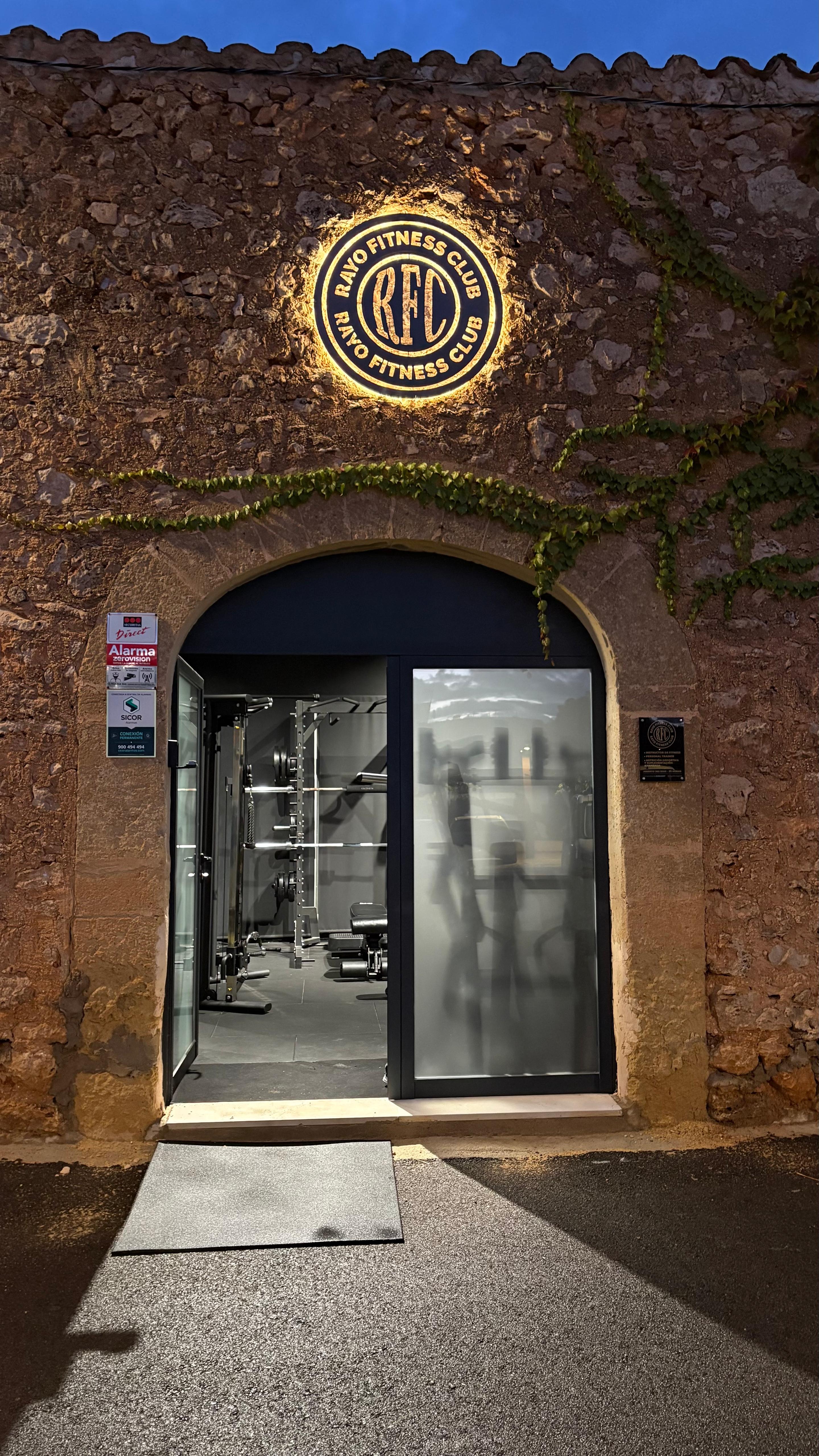 Entrada abierta de Rayo Fitness Club con vista del interior del gimnasio en Sencelles